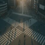 俯瞰から見下ろした夜のスクランブル交差点。人々の流れが交差し、他責思考にとらわれた心が少し冷めていくような静かな俯瞰の風景。 A high-angle view of a busy scramble crossing at night, capturing the quiet moment where the flow of people contrasts with the feeling of stepping back from blame-based thinking.